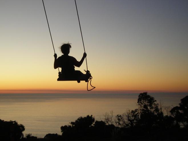 "Child swinging over the ocean"